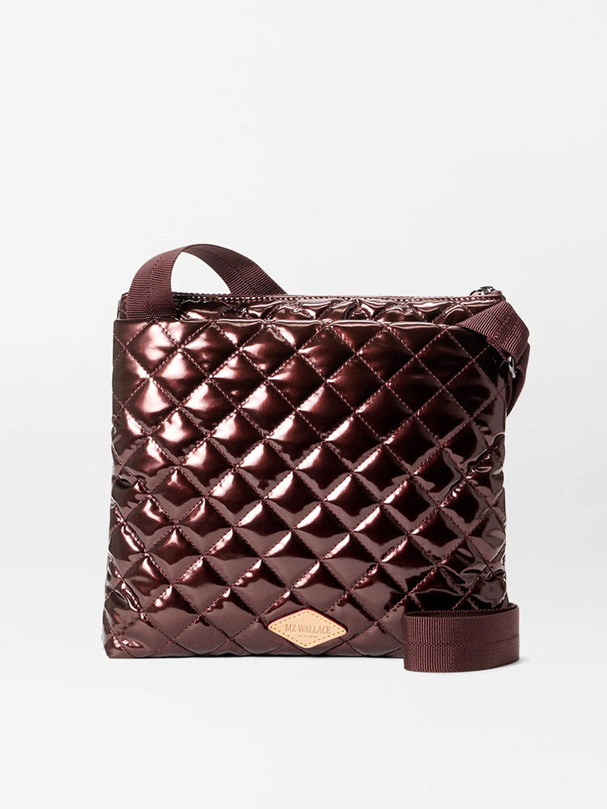 The MZ Wallace Metro Flat Crossbody in Bordeaux Lacquer Oxford features a shiny, quilted diamond pattern, adjustable strap, and front logo patch—making it a stylish, hands-free bag for any occasion.