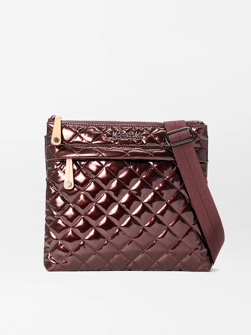 The MZ Wallace Metro Flat Crossbody in Bordeaux Lacquer Oxford features a quilted metallic burgundy finish, zippered top, front pocket, Italian leather trim, and an adjustable matching strap, shown against a plain white background.
