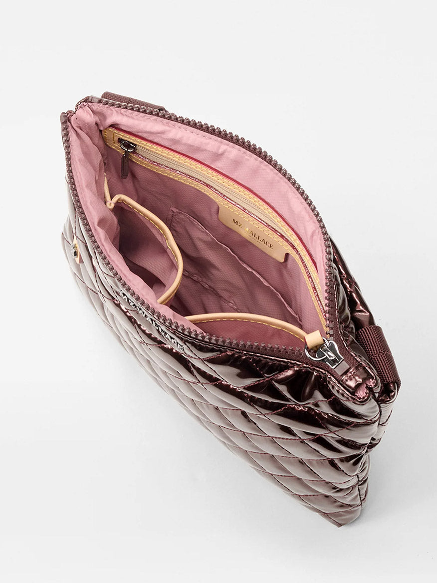 The MZ Wallace Metro Flat Crossbody in Bordeaux Lacquer Oxford features a quilted design, zippered opening, light pink lining, interior zip pocket and open pouch, plus an adjustable strap for hands-free wear.