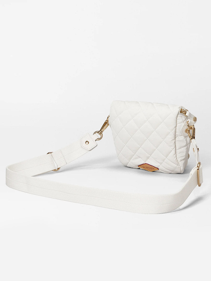 The MZ Wallace Micro Crosby Crossbody Sling in Chalk Liquid Oxford is an elegant, compact white quilted bag with an adjustable strap and gleaming gold hardware, ideal for elevating any outfit. Displayed on a plain background, it highlights its timeless design and versatility.