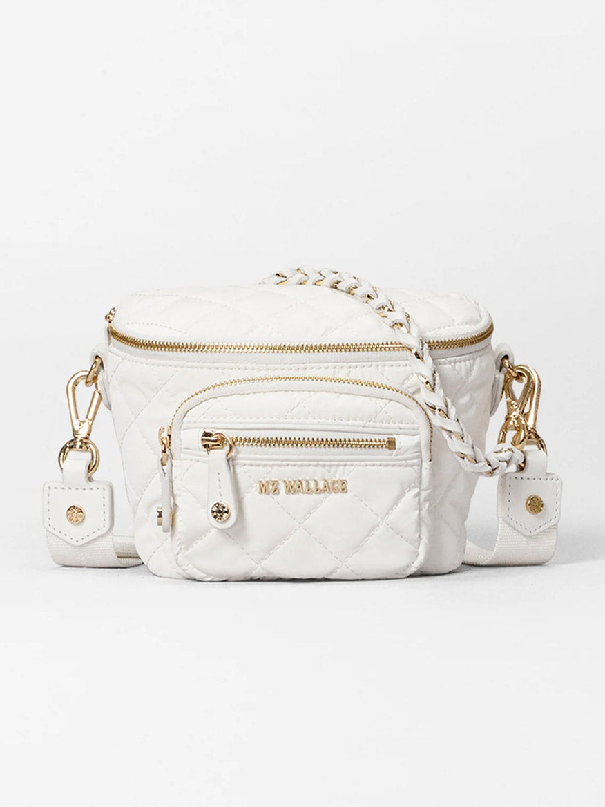 The MZ Wallace Micro Crosby Crossbody Sling in Chalk Liquid Oxford is a chic, quilted white crossbody with gold zippers and hardware, featuring a small front pocket and an adjustable chain strap for versatile wear.