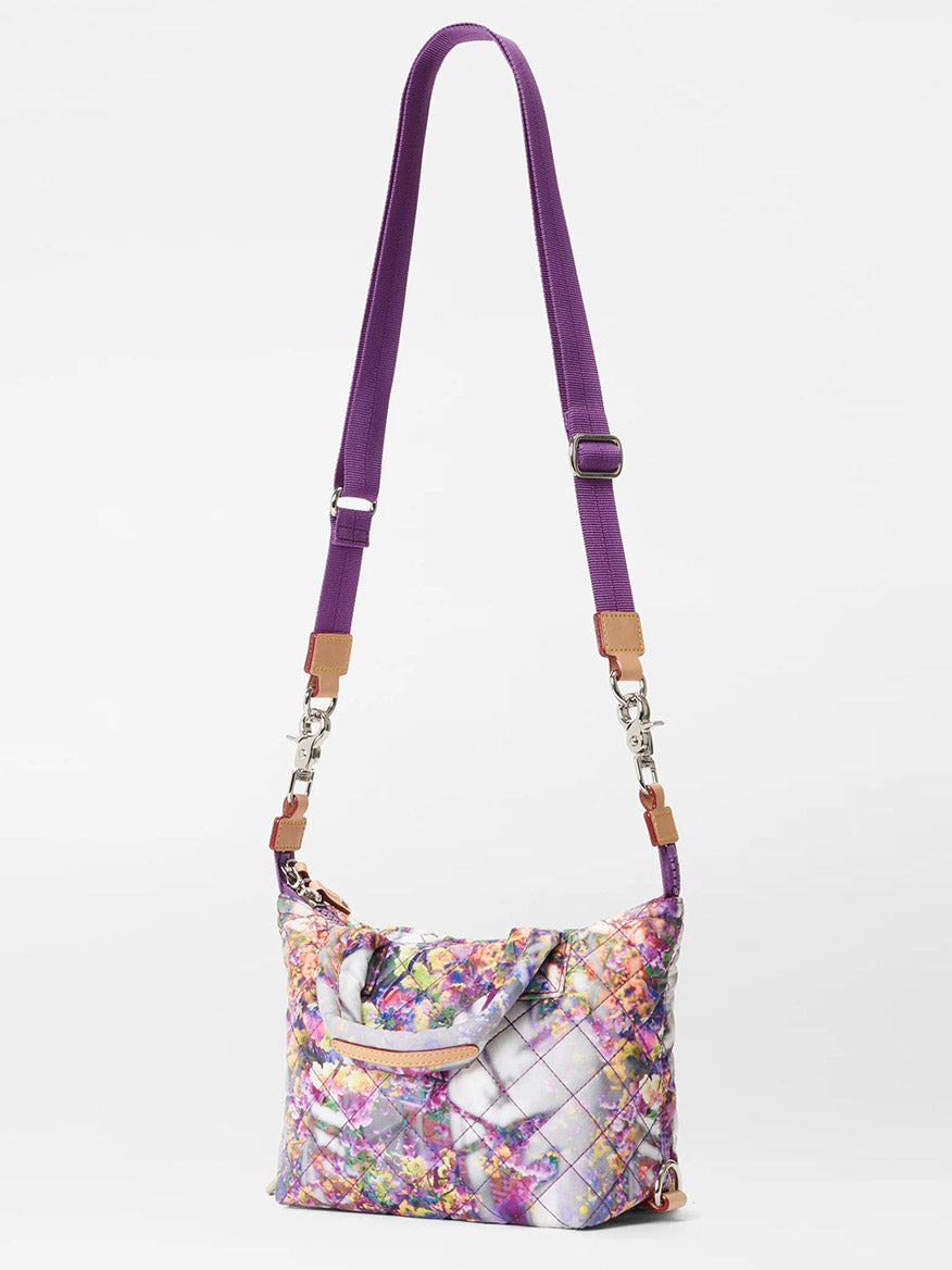 A floral quilted MZ Wallace Micro Sutton in Cherry Blossom bag featuring a vibrant purple crossbody strap and chain links, set against a plain white background.