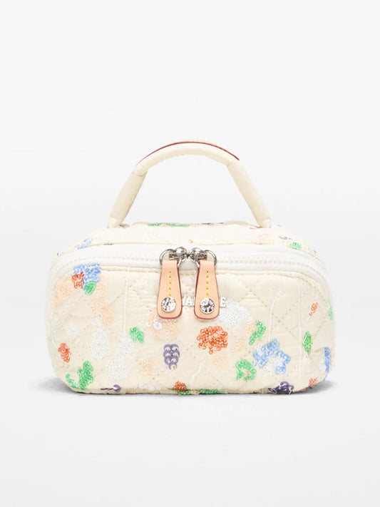 The MZ Wallace Mini Accordion Jewelry Case in Eden Sequin Oxford is a small, rectangular, cream-colored quilted bag with vibrant embroidery, a top handle, dual zippers, and multiple interior pockets for easy organization.