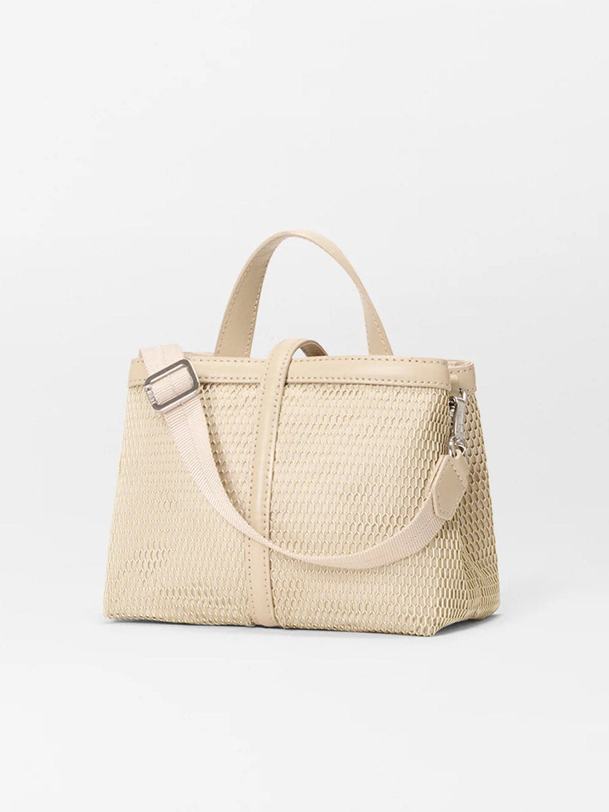 The MZ Wallace Mini Astor Top Handle in Buff Mesh is a beige woven crossbody bag with two handles and an adjustable Italian leather strap, shown against a plain white background.