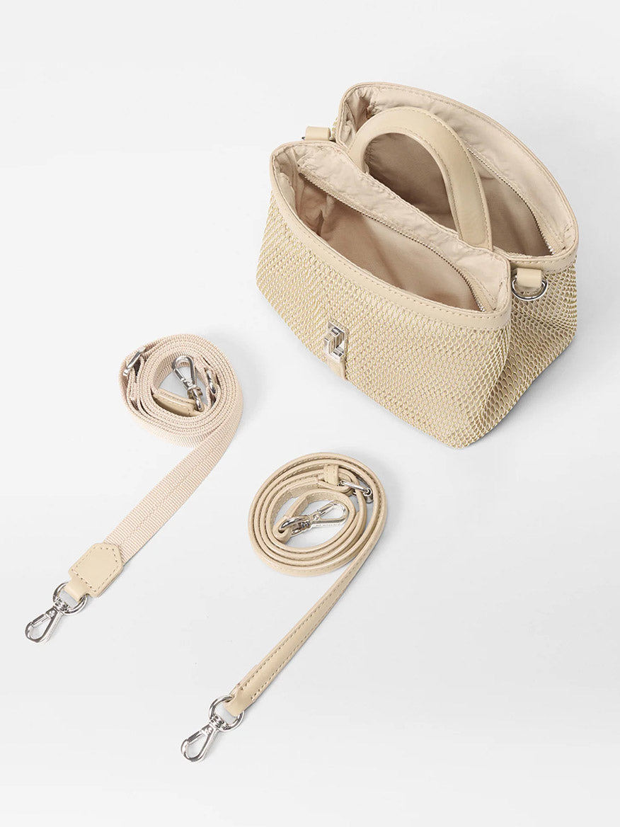 The MZ Wallace Mini Astor Top Handle in Buff Mesh features a beige woven design with an open top, showcasing its interior and two detachable Italian leather straps for versatile styling.