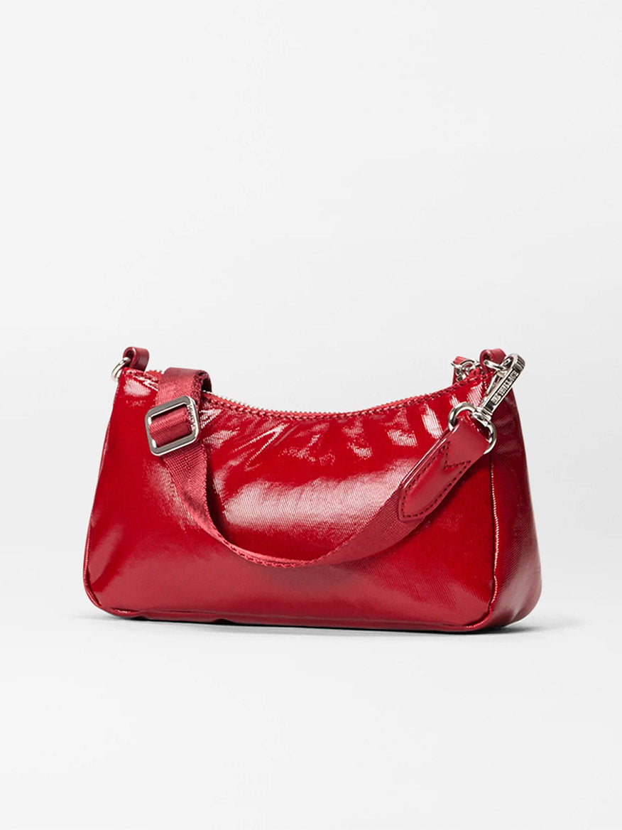 The MZ Wallace Mini Chelsea Shoulder in Apple Gloss Bedford features a small, shiny red design with a short strap and silver hardware, crafted from Bedford fabrication with Italian leather trim, shown on a plain white background.