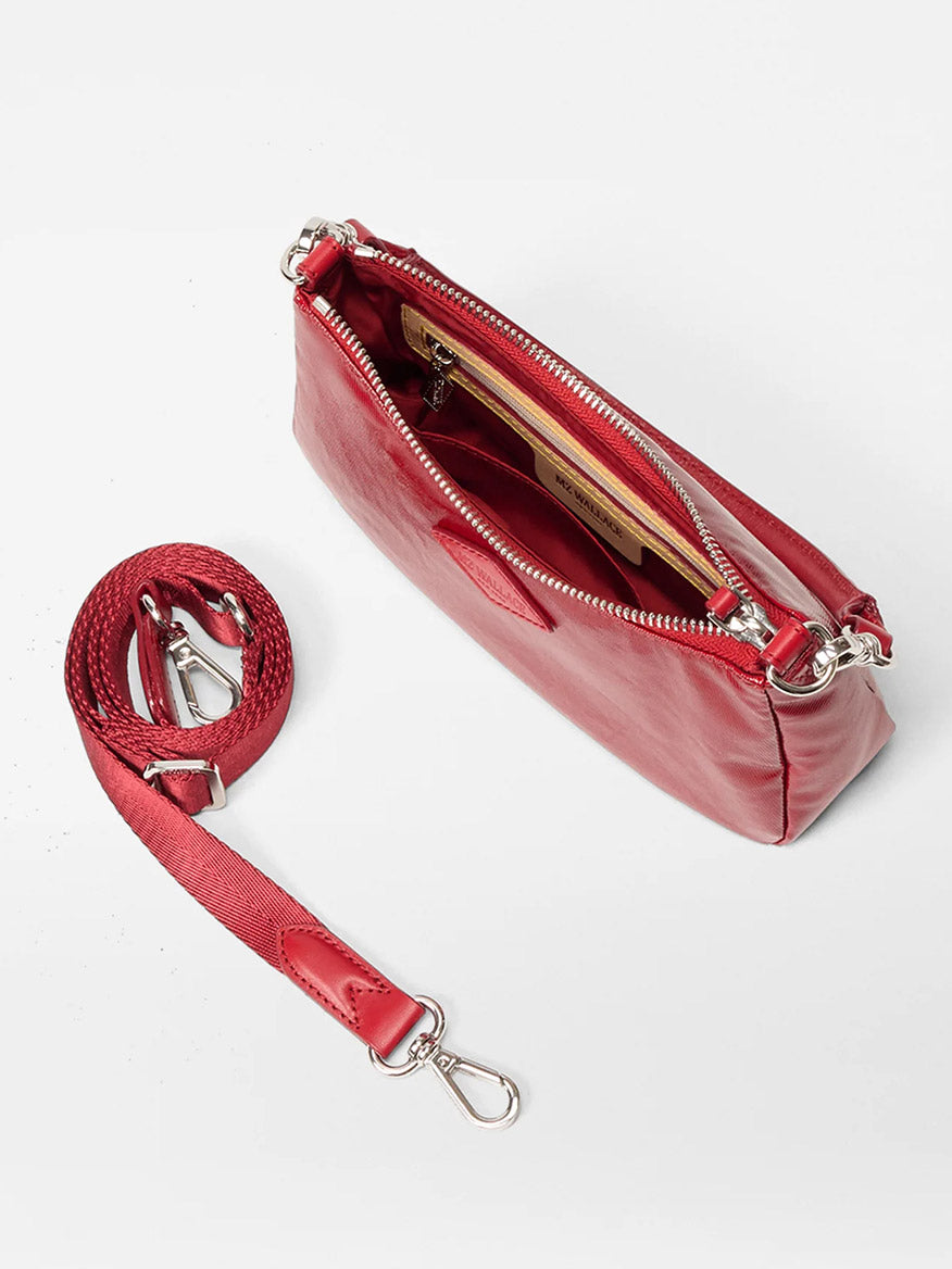 The MZ Wallace Mini Chelsea Shoulder in Apple Gloss Bedford is shown from above with the zipper open, revealing an inner pocket holding cards. This red crossbody features Italian leather trim and a detachable strap.