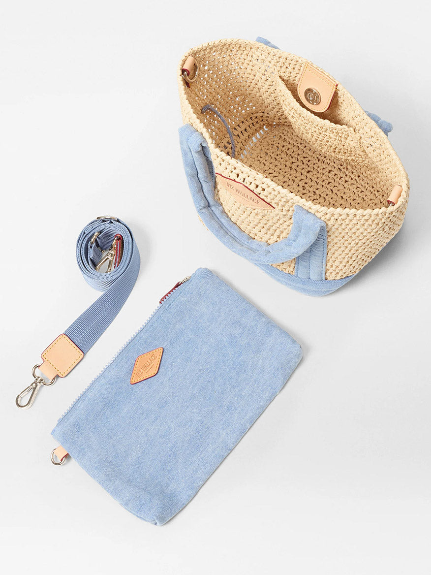 The MZ Wallace Mini Crochet Tote in Crochet/True Light Denim features a woven straw design with blue fabric handles, an adjustable crossbody strap, and a matching blue fabric pouch, all set against a white background.