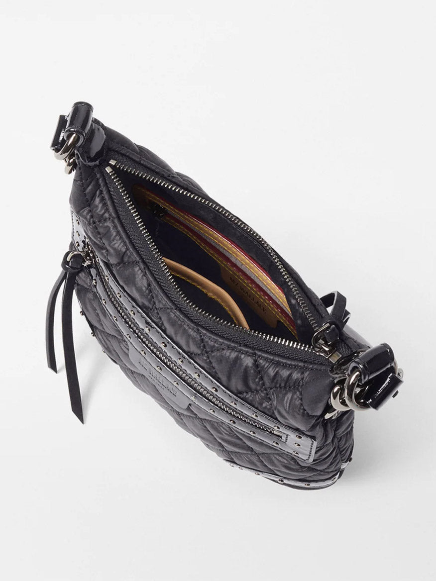 The MZ Wallace Mini Multi Stud Crosby Sienna in Black Stud & Suede is a black quilted handbag with an open zipper, striped fabric interior, multiple pockets, and Italian leather trim, displayed on a white surface.