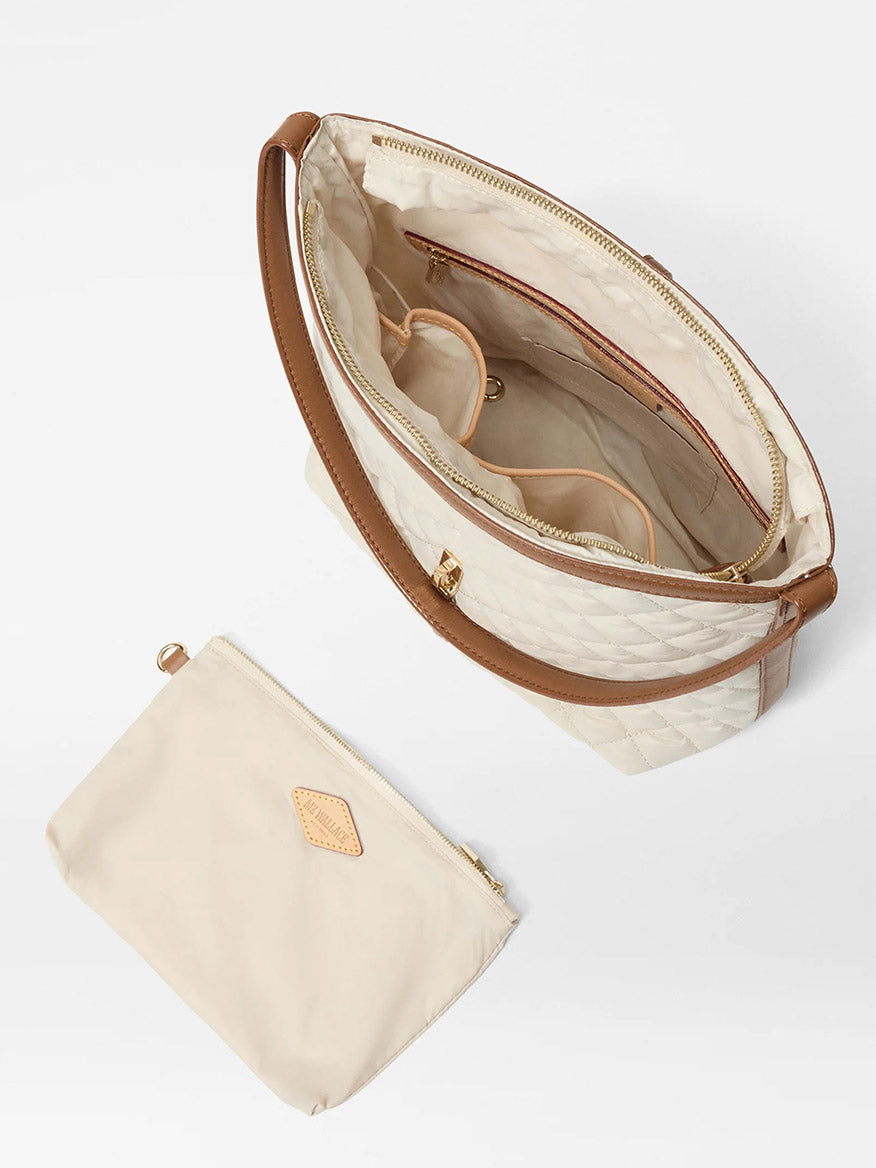 The MZ Wallace Small Astor Hobo in Sandshell Oxford With Brown features a beige quilted nylon exterior, brown handle, Italian leather trim, interior pockets and compartments, and comes with a matching beige zippered pouch.