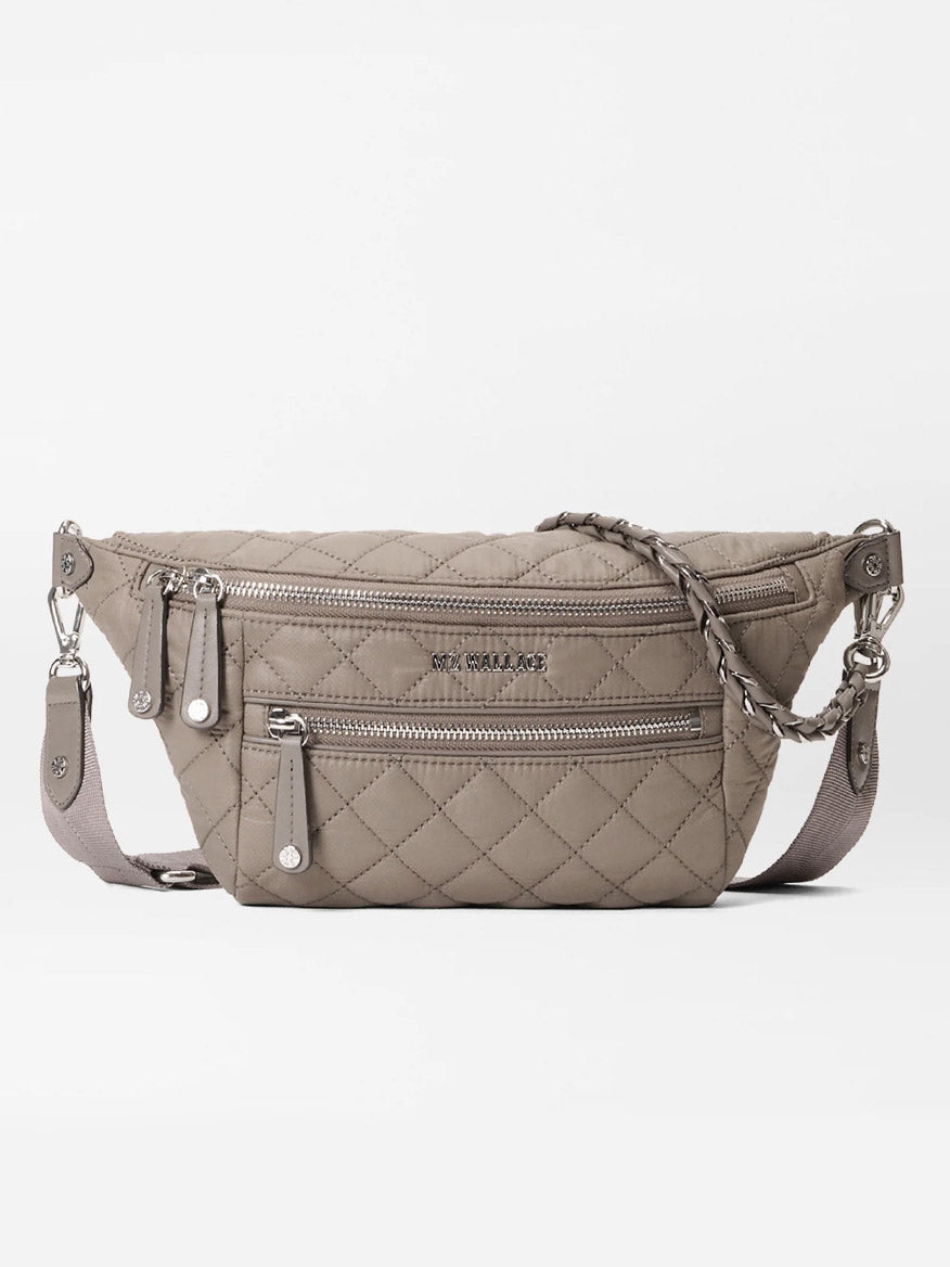 The MZ Wallace Small Crosby Sling Bag in Morning Dove Oxford is a quilted crossbody with two zippered compartments, a braided zipper pull, and an adjustable shoulder strap, shown on a white background.