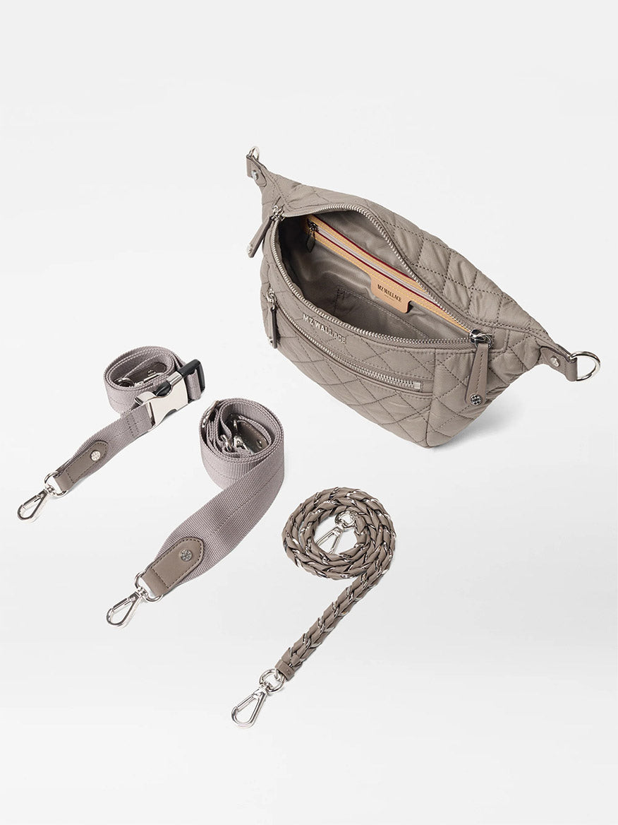 The MZ Wallace Small Crosby Sling Bag in Morning Dove Oxford features quilted gray fabric, a zippered compartment, and comes with two detachable straps—one woven and one padded—displayed on a white background.