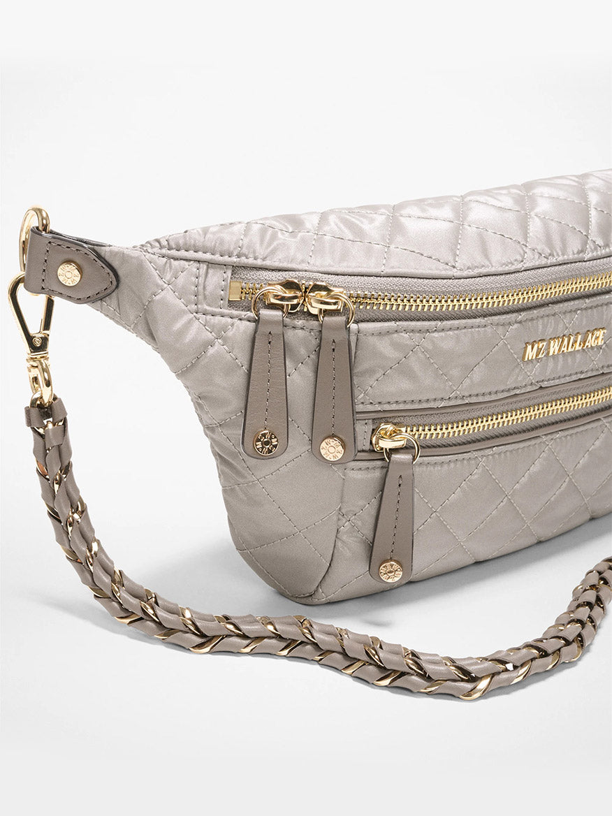 The MZ Wallace Small Crosby Sling Bag in Sable Pearl Metallic Oxford features gold zippers, two front zip pockets, a braided strap with gold hardware, and the "MZ WALLACE" logo in gold on the front.