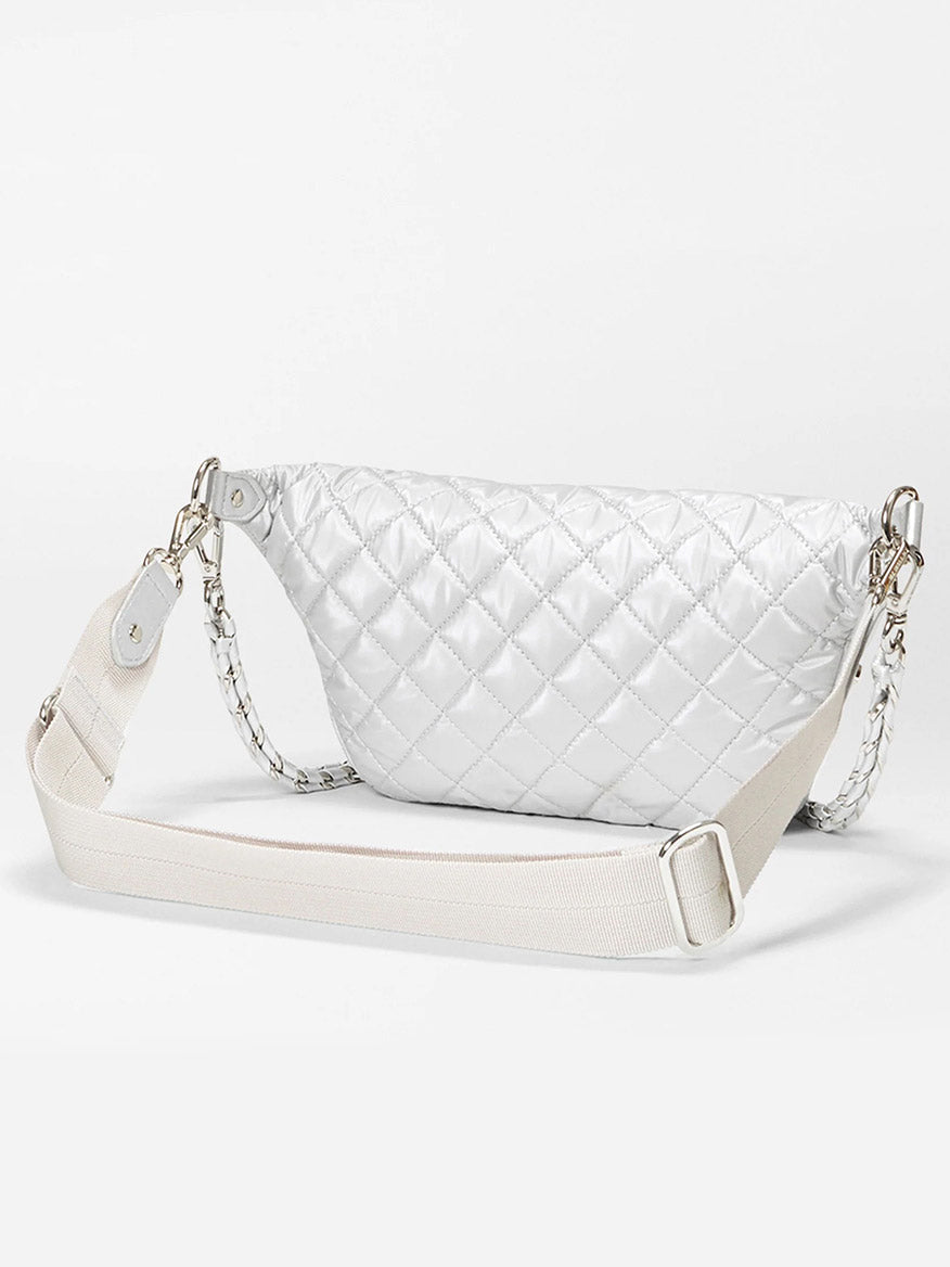 The MZ Wallace Small Crosby Sling Bag in Oyster Metallic Oxford features a white quilted design, wide adjustable strap, and silver hardware, crafted from durable Oxford fabrication. It is displayed against a plain white background.