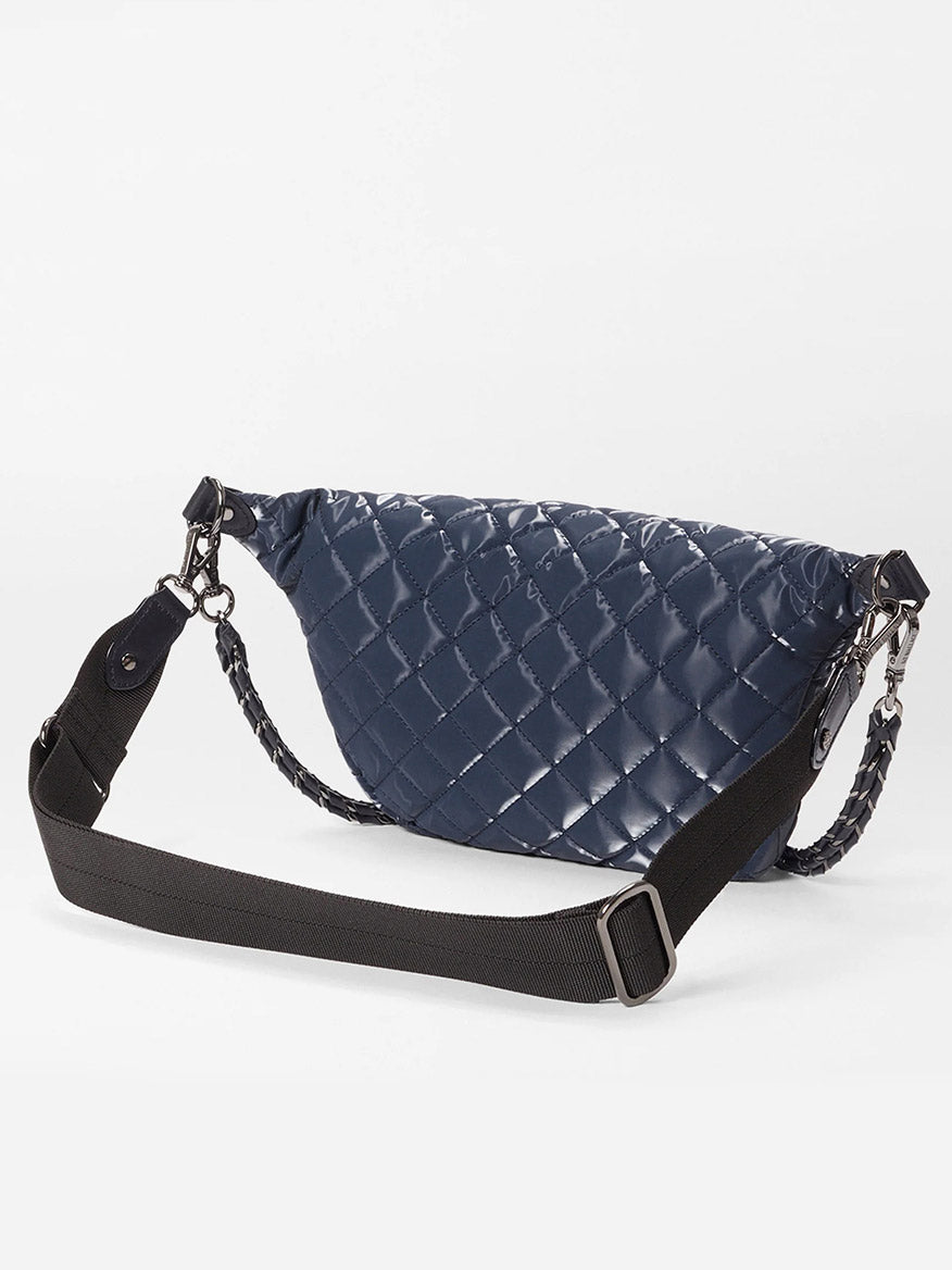 The MZ Wallace Small Crosby Sling Bag in Ink Liquid Oxford features a glossy navy blue quilted finish and an adjustable black shoulder strap, shown against a white background.