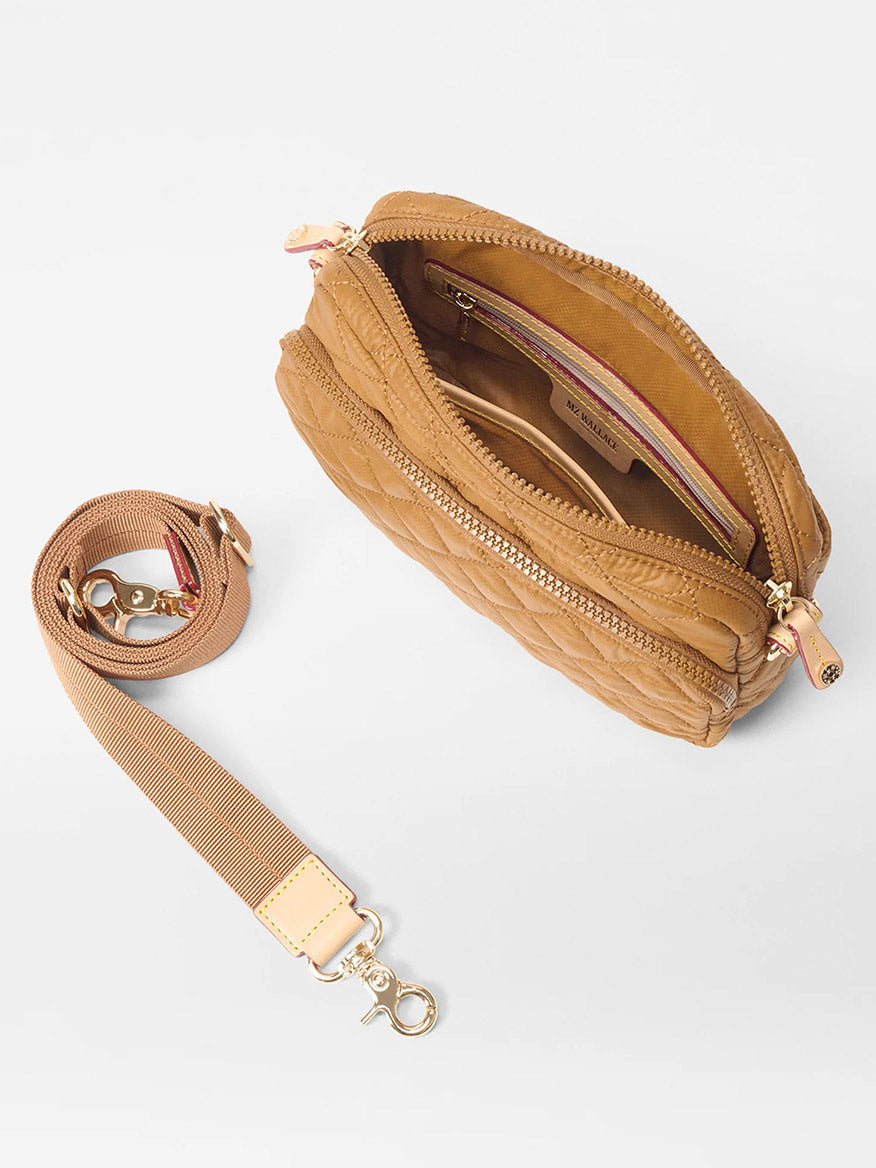 The MZ Wallace Small Metro Camera Bag in Amber Oxford features quilted nylon with gold zippers, interior pockets, and a matching removable strap with gold clasps. Shown on a white background, it's a chic, lightweight bag for everyday use.