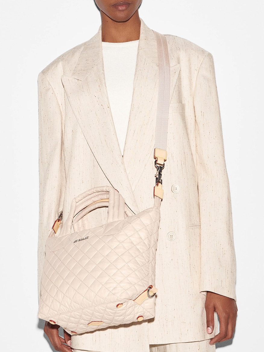 Person wearing a textured blazer and carrying a MZ Wallace Small Sutton Deluxe in Mushroom Oxford with crossbody strap.