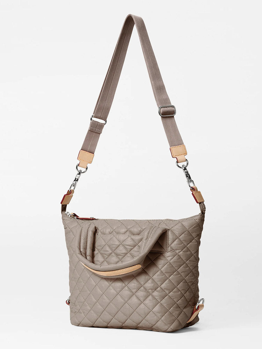 The MZ Wallace Small Sutton Deluxe in Morning Dove Oxford features a taupe quilted design, Italian leather trim, adjustable crossbody strap, dual handles, and silver-tone hardware on a plain white background.