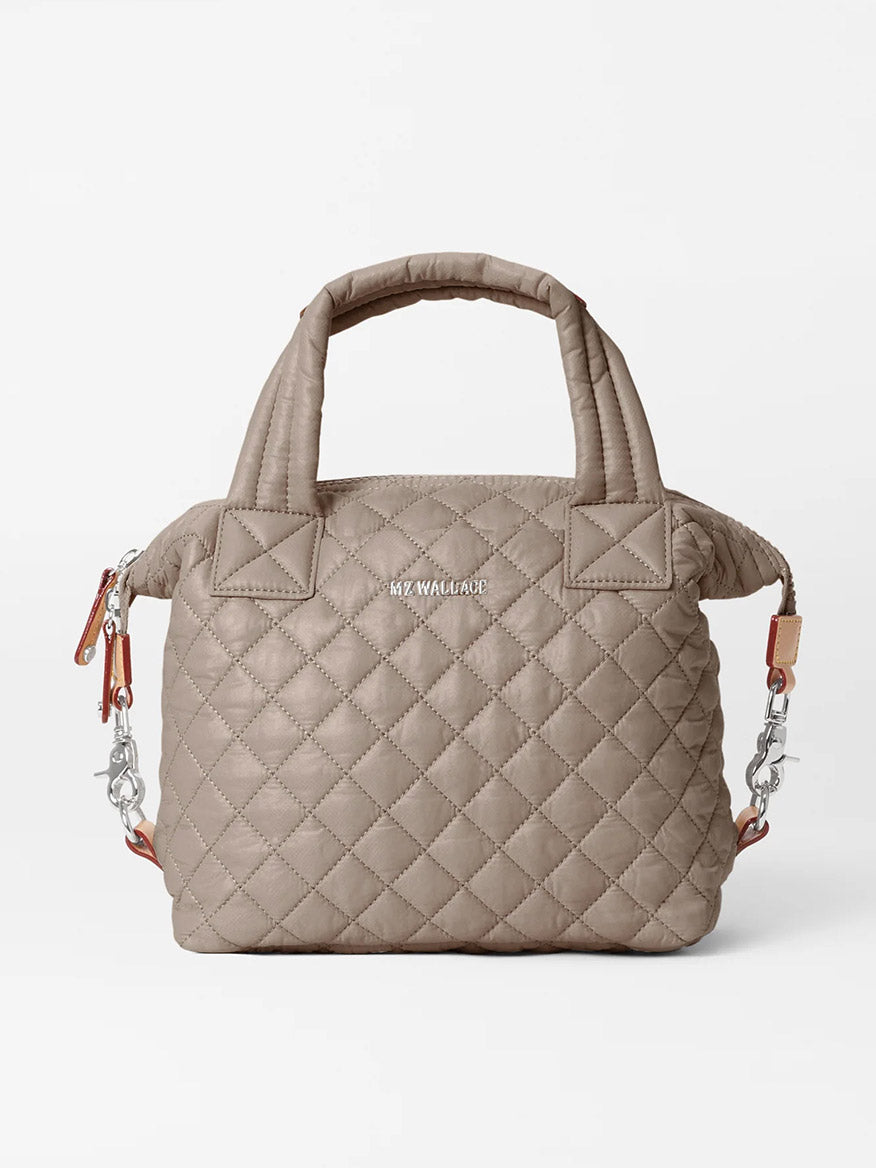 The MZ Wallace Small Sutton Deluxe in Morning Dove Oxford is a quilted taupe crossbody bag with dual top handles, a detachable chain strap, zip closure, and "MZ WALLACE" in silver letters on the front.