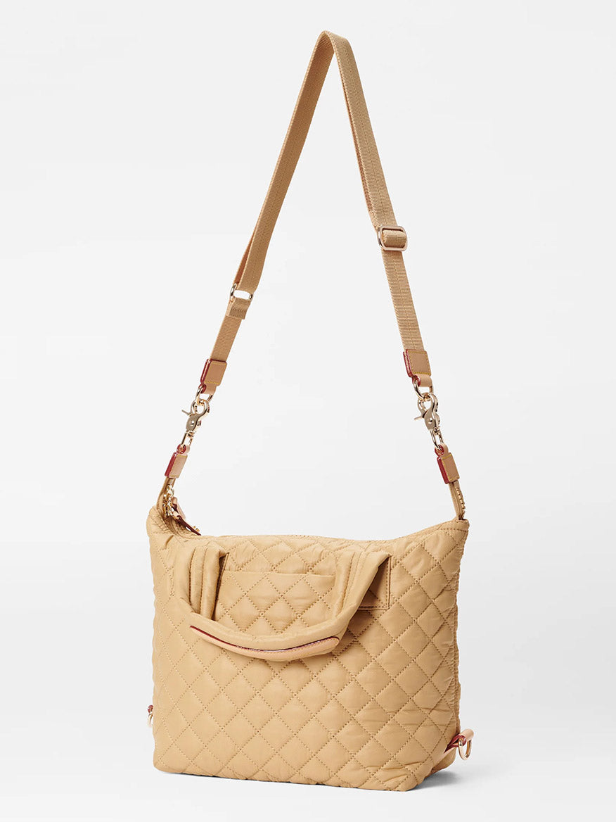 MZ Wallace Small Sutton Deluxe in Camel Oxford beige quilted shoulder bag with adjustable crossbody strap and external pocket against a white background.