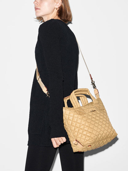 Woman in a black outfit carrying a MZ Wallace Small Sutton Deluxe in Camel Oxford tote bag with nylon handles.