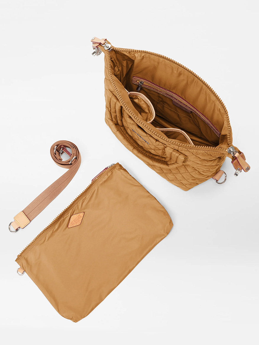 The MZ Wallace Small Sutton Deluxe in Amber Oxford is displayed on a white background, featuring interior compartments, a detachable strap, and a matching zippered pouch placed beside the bag.