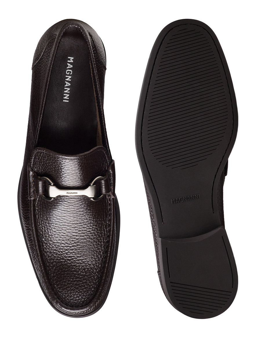 Brown leather loafers with a textured finish feature metal detailing on top, similar to classic bit loafers. One shoe is side-viewed while the other shows its cushioned sole. Both are labeled "Magnanni Gentry Soft in Tumbled Brown.