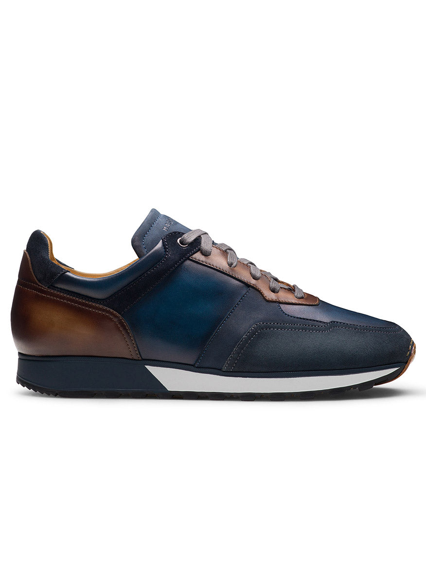 The Magnanni Arco in Navy/Brown is a leather sneaker featuring a lace-up front, hand-stitched leather toe, and classic runner sole. Designed for casual wear, it boasts a subtle gradient effect on the upper.