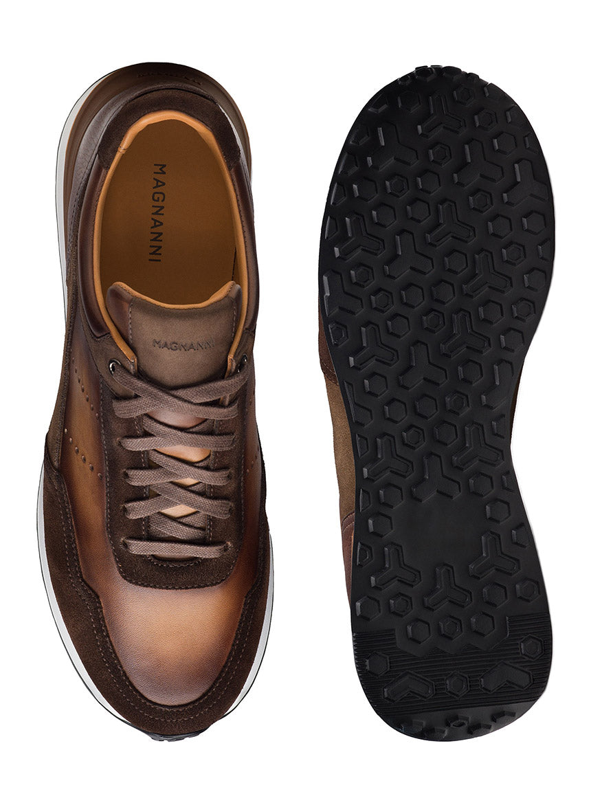 Top and sole view of the Magnanni Bravo V men's sneaker in midbrown suede/brown, showcasing an athletic design, luxury materials, a textured black rubber outsole, and a refined gradient effect.