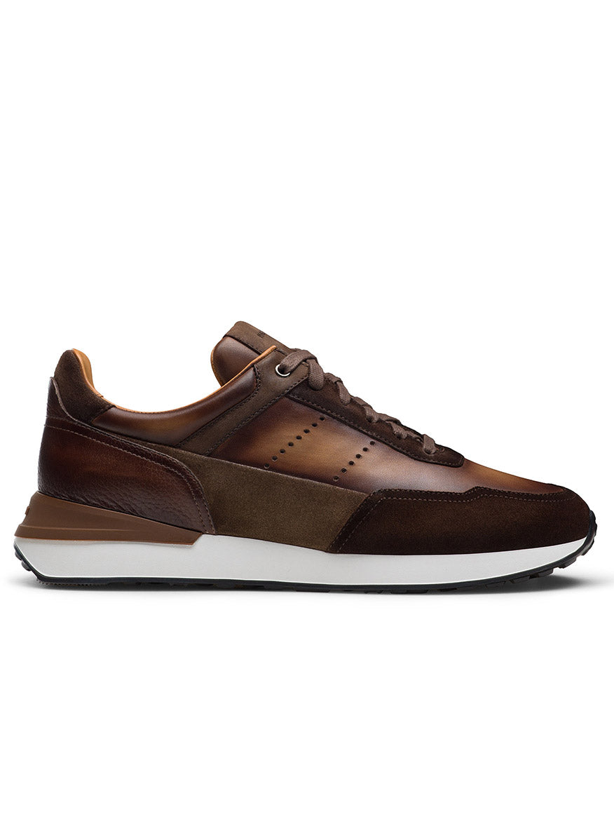 The Magnanni Bravo V in Midbrown Suede/Brown is a luxury men's sneaker with full-grain brown leather and suede, a white midsole, dark outsole, lace-up closure, shown in a sleek side profile view.