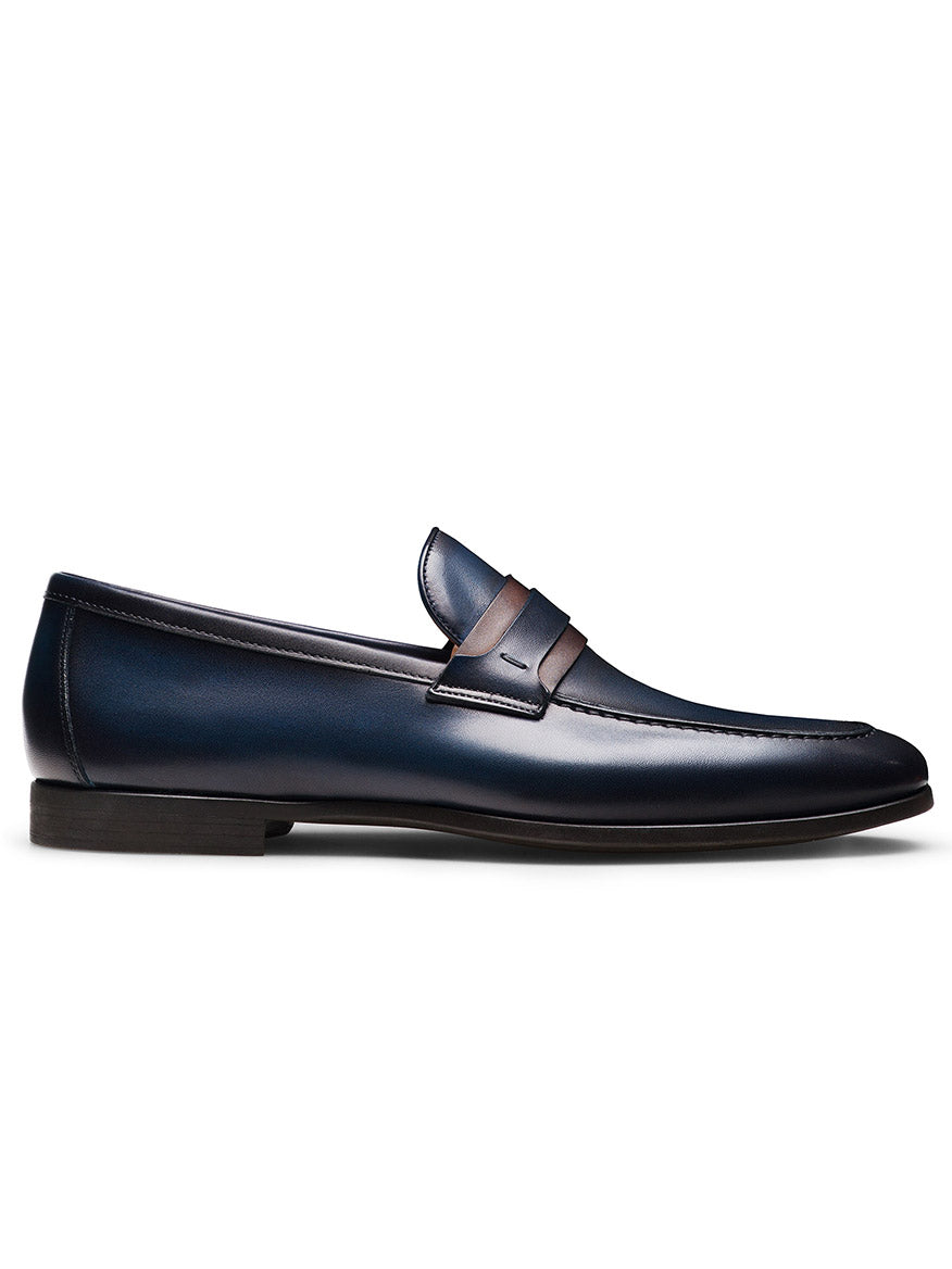 A single Magnanni Daniel in Navy/Midbrown penny loafer from the Línea Flex collection, made in Spain with dark blue leather, midbrown accents, a low black heel, and penny strap, shown in profile on a white background.
