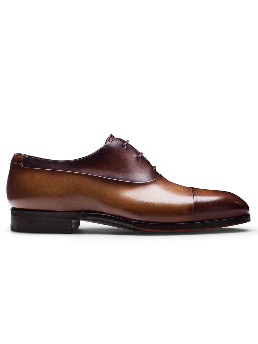 The Magnanni Duke in Tabaco/Brown is a brown leather oxford shoe with a glossy finish, cap-toe design, and dark sole. Experience luxurious craftsmanship and sophistication with every step.