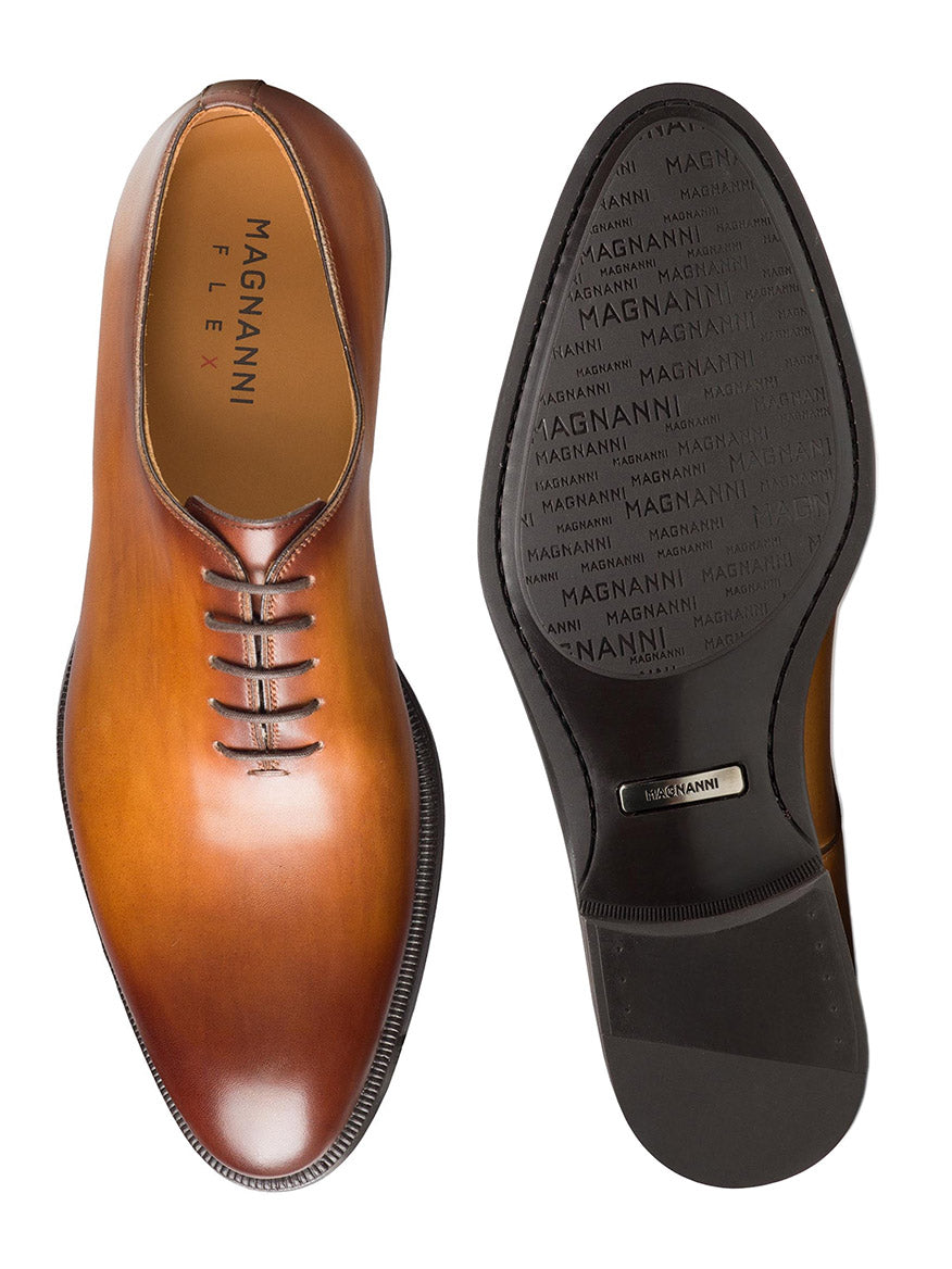 A top and bottom view of a polished brown leather derby dress shoe with the brand name "Magnanni Hawkins in Cuero" visible, featuring Bologna construction.