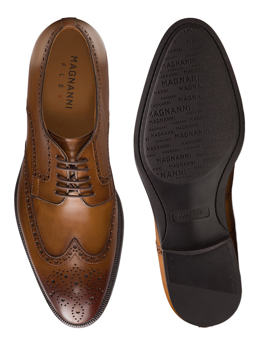 The Magnanni Heyward in Tabaco is a pair of brown leather brogue wingtip derby shoes with intricate detailing, shown from the top and bottom. The sole displays the "Magnanni" brand name multiple times.