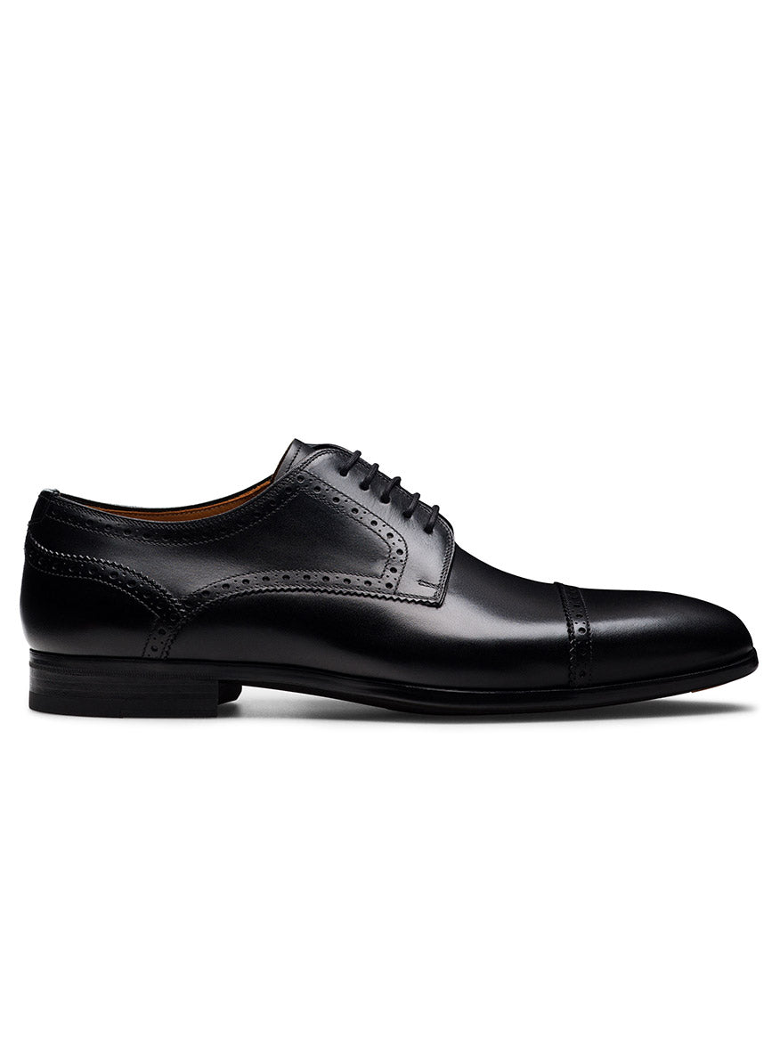 The Magnanni Macsen in Black is a leather brogue dress shoe with a cap toe and decorative stitching, shown side-on against a white background—ideal for luxury footwear enthusiasts.
