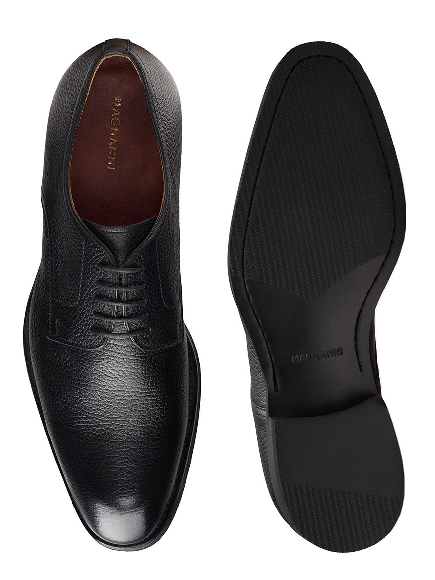 The Magnanni Melich V in Tumbled Black is a pair of black leather lace-up dress shoes with subtle textured detailing, shown from the top and sole—perfect for a polished, smart-casual look.