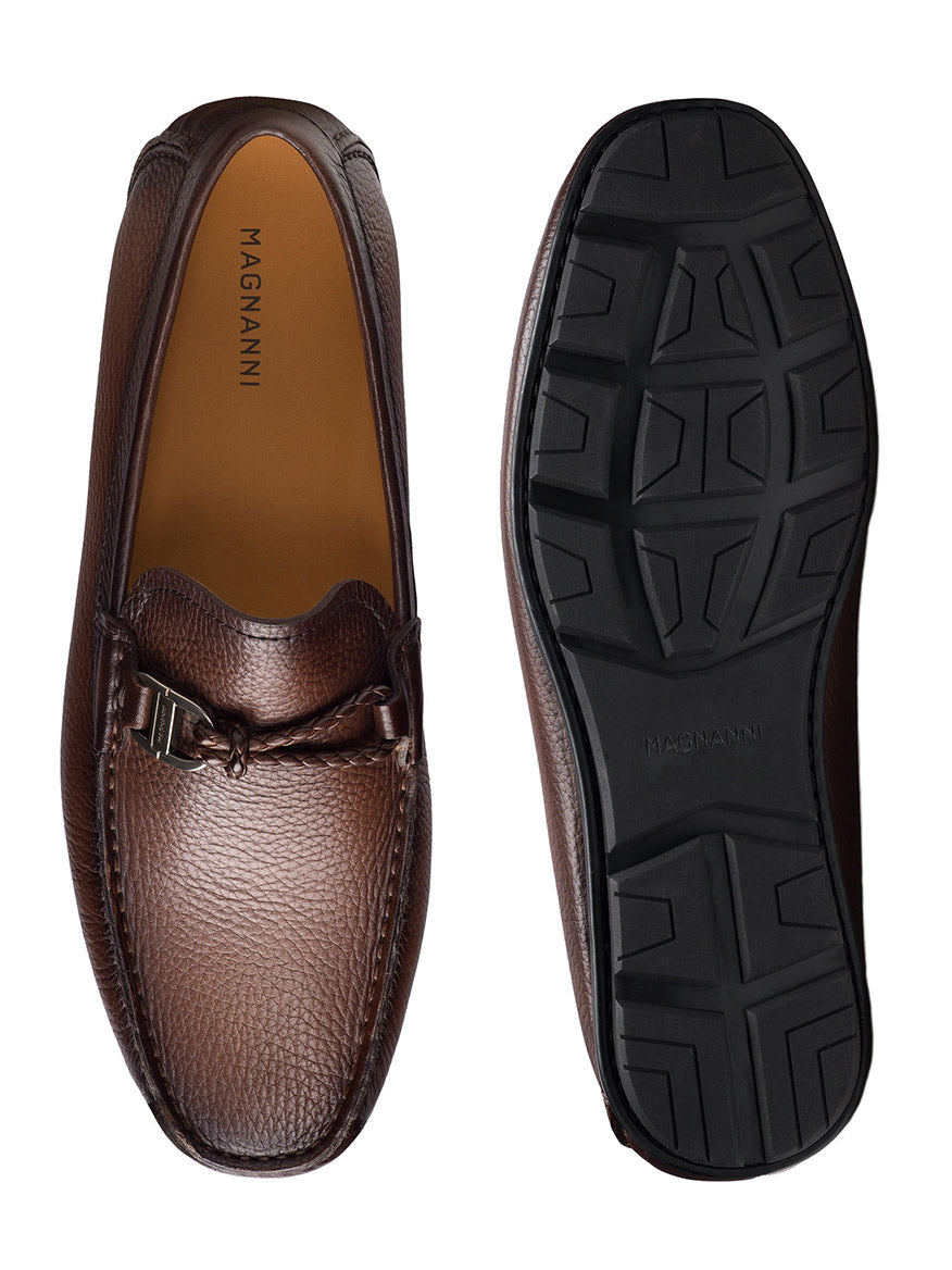 The Magnanni Monterey Braid Bit in Tumbled Brown showcases brown leather loafers with buckle detail and braided leather accents, displayed from top and bottom views. They feature a driving loafer design with a textured black rubber sole for optimal grip.
