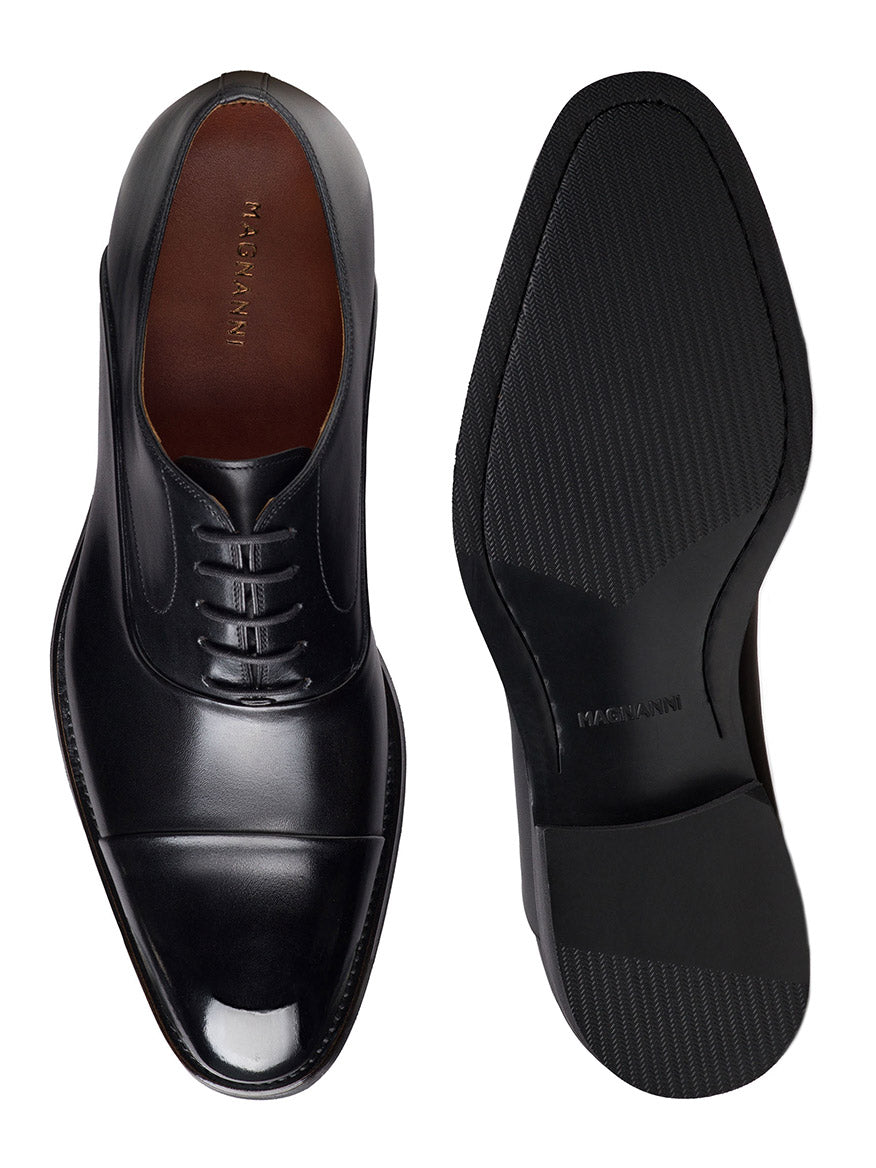 The Magnanni Omega in Black embodies timeless elegance, showcasing one Oxford shoe's top view with laces and the other's intricate sole texture, crafted from premium calfskin.
