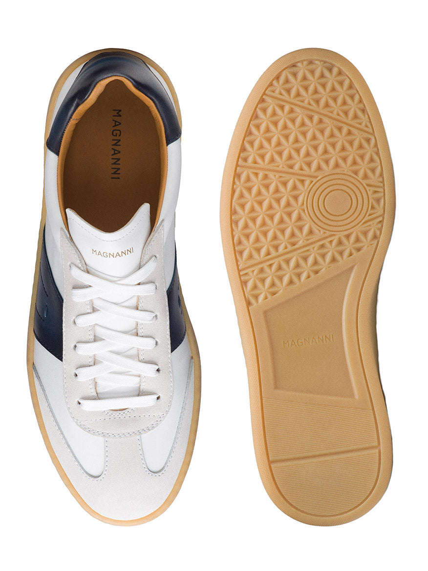 Magnanni Primera sneakers in White/Navy feature a gum sole and navy detailing. Shown from the side and sole view, the brand name is visible on both the insole and sole. Crafted from premium suedes to add a touch of elegance.