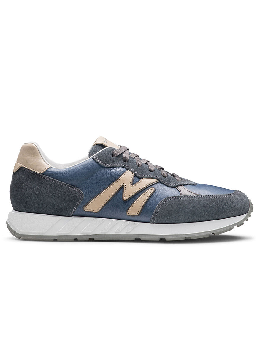 The Magnanni Yoki in Indigo Suede/Cream is an athletic sneaker featuring gray laces and an "M" emblem, exuding a timeless retro aesthetic. Displayed against a white background.