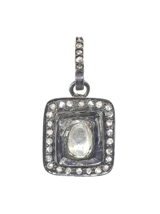 A Margo Morrison Square Shape Raw Diamond Charm with a central oval clear stone, surrounded by smaller clear stones set in a dark metal frame, and an ornate, studded loop at the top for a sterling silver chain.