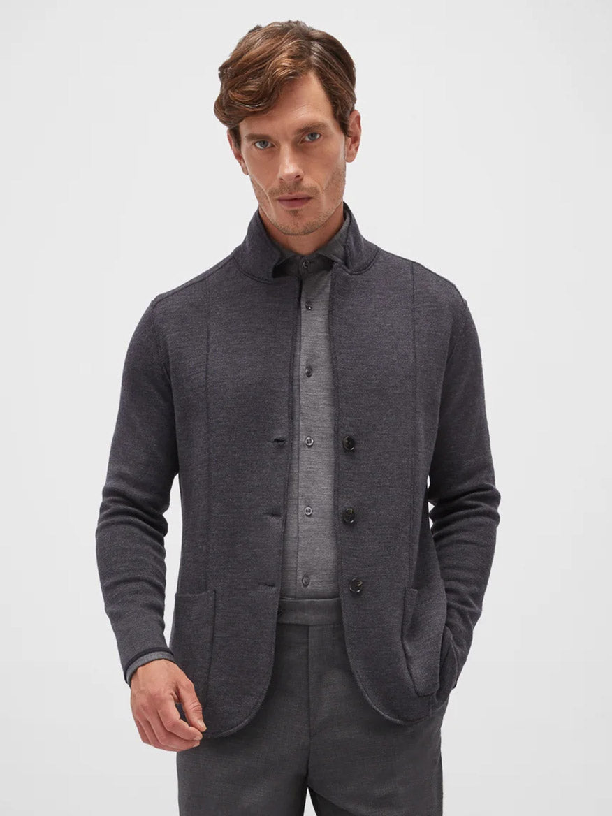 A man with short brown hair wears a Maurizio Baldassari Jamaica Reversible Wool Swacket in Navy/Charcoal over a light grey shirt. He is standing against a plain white background with one hand in his pocket.