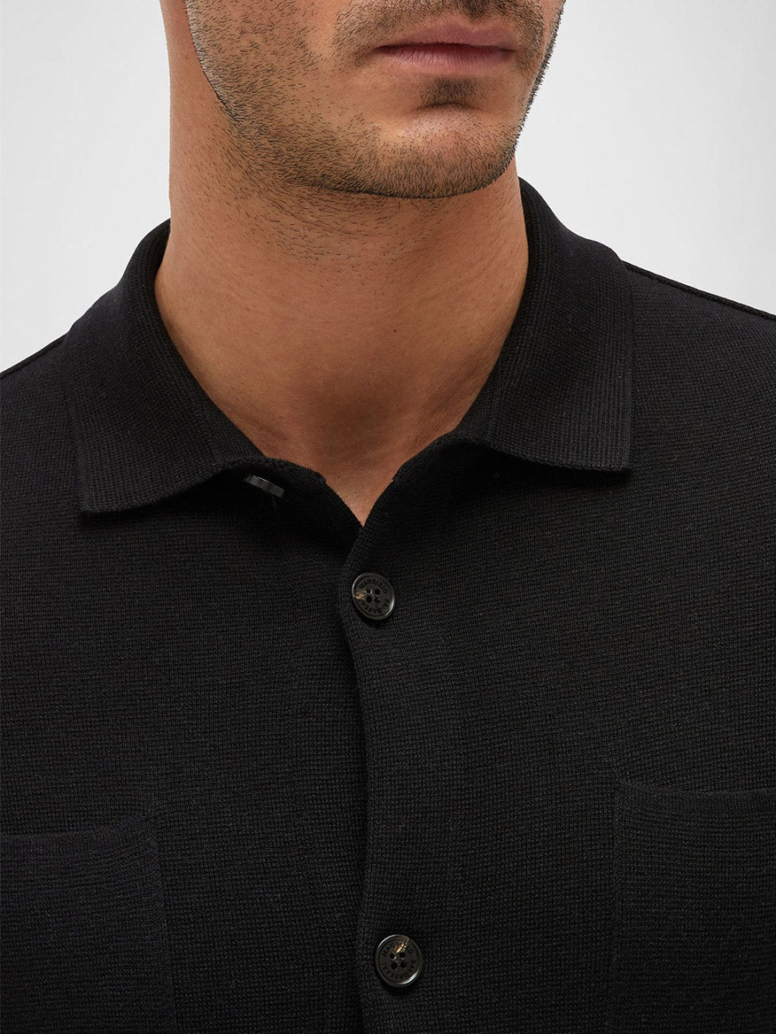 Close-up of a man wearing a Maurizio Baldassari Silk & Cotton Overshirt in Black with visible buttons. Only the neck and lower face are shown.