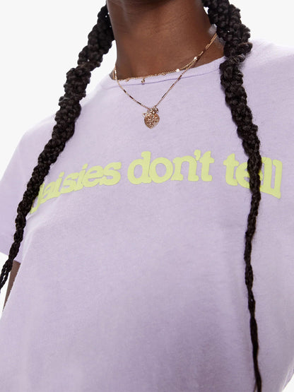 Close-up of a person wearing a Lavender Mother Denim The Boxy Goodie Goodie tee with the phrase "daisies don't tell" in green, accessorized with a heart-shaped necklace.