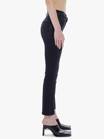 A person wearing dark Mother Denim The Dazzler Mid Rise Ankle in Deep End jeans and black high heels standing sideways against a white background.