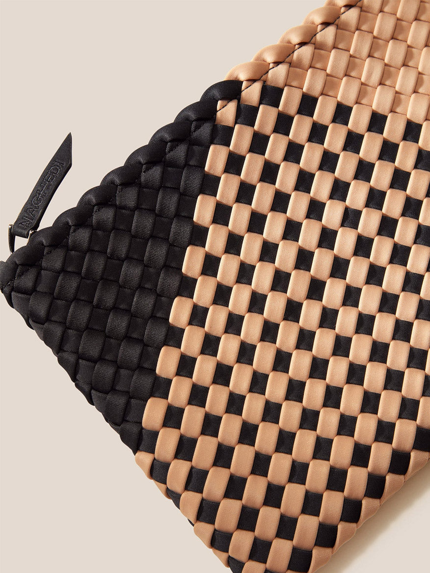 Close-up of a Naghedi St. Barths Medium Tote in Plaid Cabana with an intricate black and beige handwoven neoprene design and a visible brand tag.