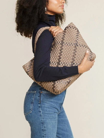 Woman in a turtleneck and jeans holding a large handwoven Naghedi St. Barths Medium Tote in Plaid Mojave.