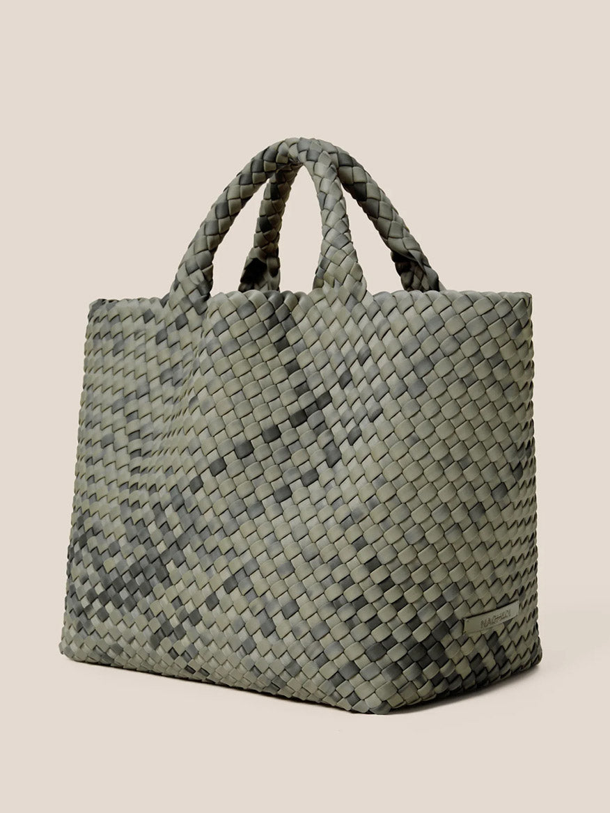 The Naghedi St. Barths Medium Tote in Watercolor Neptune is a handwoven neoprene bag in a lush green shade, featuring two short handles that stand out elegantly against the beige background. Perfect as an everyday accessory, this tote combines stylish design with practical construction.