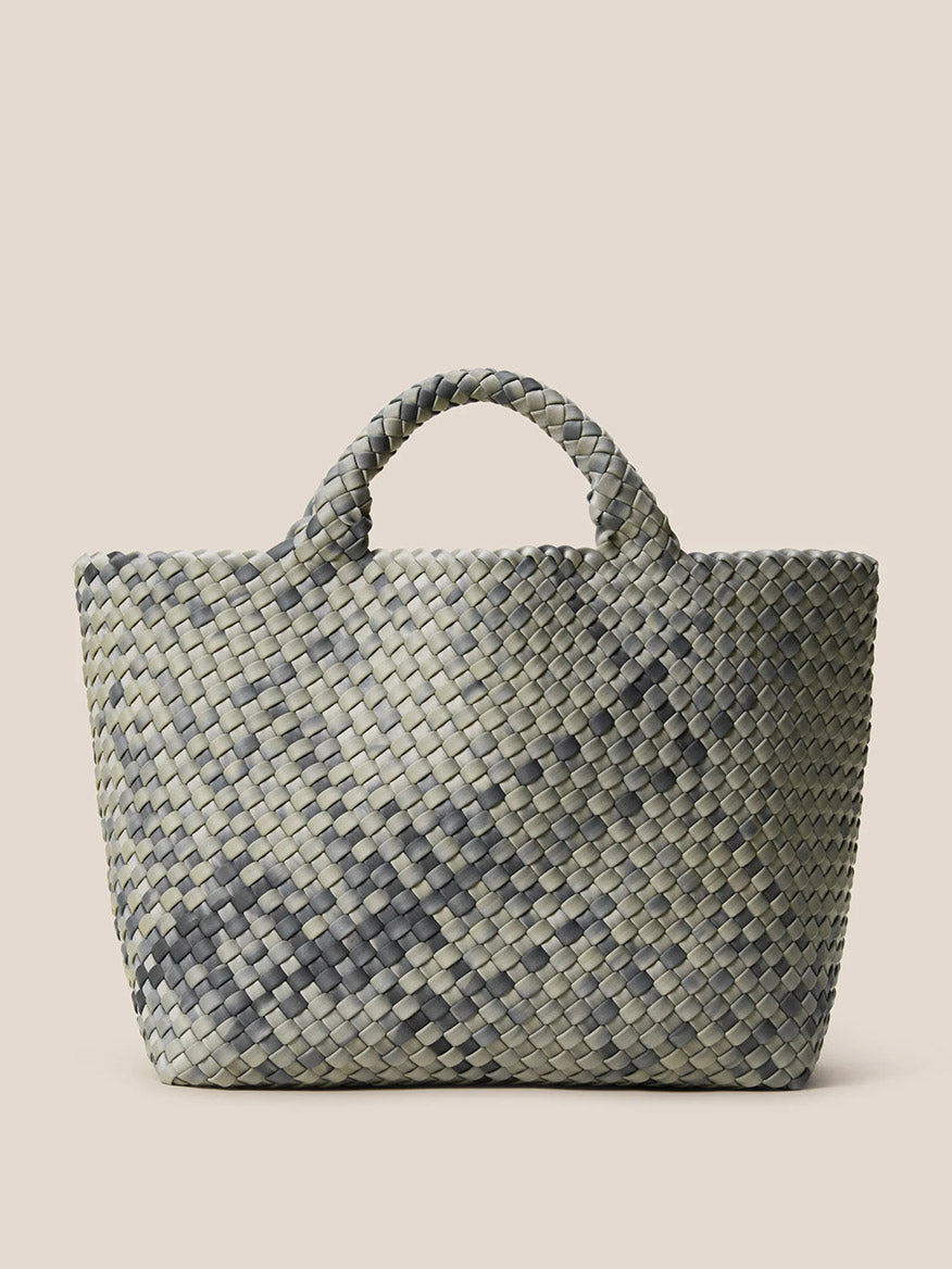 The Naghedi St. Barths Medium Tote in Watercolor Neptune is an everyday bag that boasts a camouflage pattern, meticulously crafted from handwoven neoprene and equipped with two sturdy handles, all set against a plain background.