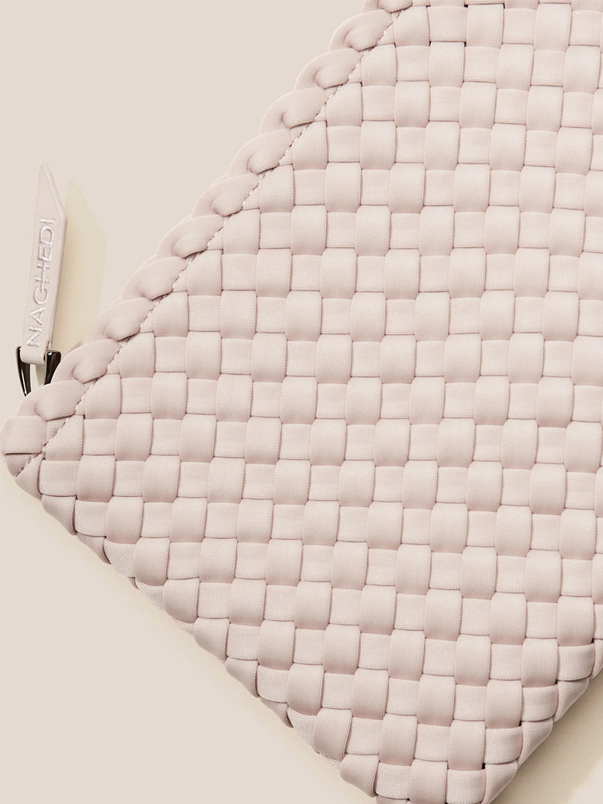 Close-up of a textured Naghedi St. Barths Small Tote in Solid Shell Pink clutch with a brand tag.